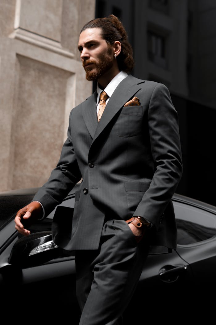 Sophisticated businessman in suit walking past a luxury sportscar in a city setting.